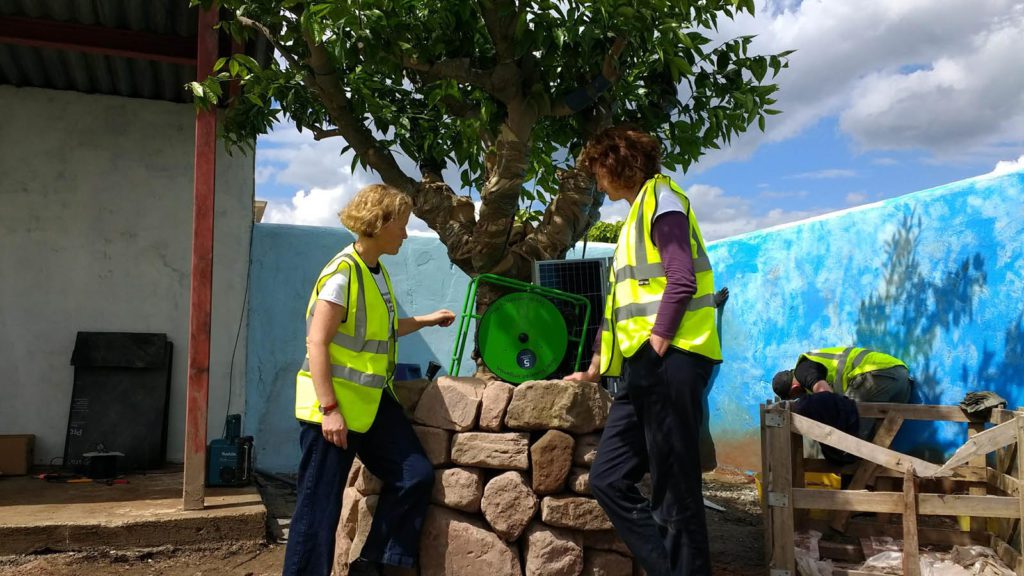 Designer Jilayne and Charlotte from DFID discuss the Futurepump SF2 in front of an orange tree