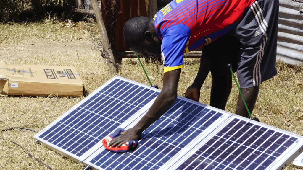 A farmer cleaning the solar panels of an SF2 water pump. This minor maintenance is part of the advantages and disadvantages of solar.