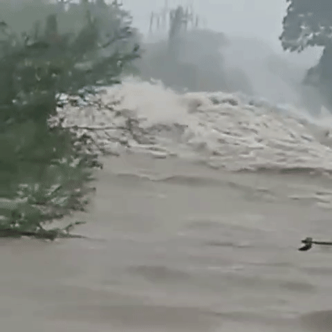 A gif showing rushing grey-brown water, a dangerous flood.