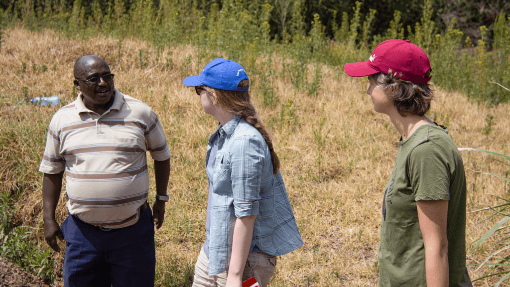 A black man called Peter shows white women Freya and Martina from Futurepump around his farm during the dry season.